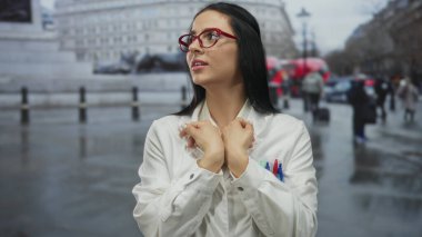 Laboratuvar önlüklü bir kadın, kırmızı otobüslerle çevrili bir Londra caddesinde dikiliyor, İspanyol mirasını şehir zemininde sergiliyor..