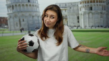 İtalya 'da Pisa Tower' da elinde futbol topu tutan bir kadın gün içinde canlı bir arka plana karşı neşeli bir ifade sergiliyor.