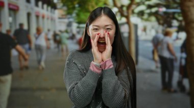Kalabalık bir şehir sokağında neşeli bir şekilde bağıran kadın canlı şehir yaşamını ve çeşitli yayaları güneşli bir günde harekete geçiriyor..