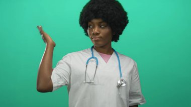 Steteskoplu genç Afrikalı Amerikalı kadın doktor avuç içini kaldırdı ve stüdyoda başını eğdi; şefkat desteği.