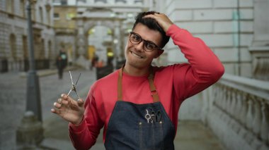 Şehrin caddesinde elinde makas tutan genç İspanyol adam gözlüklü önlüklü gülümsüyor. Dışarıdan kendine güvenen dış plan resmine benziyor..