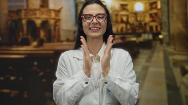 Beyaz önlüklü, kırmızı gözlüklü bir kadın kilise ortamında bilim ve maneviyatın bir karışımını gösteren ifadeler kullanıyor..