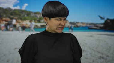 Genç Asyalı bir kadın, güneşli bir sahil gününde neşeli bir arka planda tiksinti ifadesi sergiliyor..