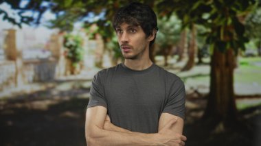 İnsan kollarını çapraz ve yanlamasına yeşil ormanda yüksek meşe ağaçları arasında benekli güneş ışığı altında; sessiz tefekkür.