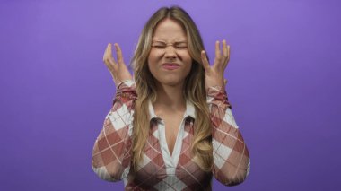 Ekose gömlek giyen bir kadın stüdyoda yumruklarını sıkar ve gözlerini sıkar..