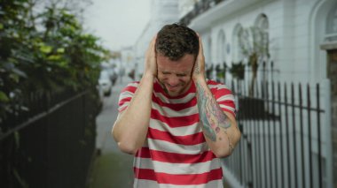 Çizgili gömlekli bir adam şehir sokaklarında dikiliyor. Hayal kırıklığını ve duyguları ifade ediyor. Gözler kapalı ve eller başının üstünde..