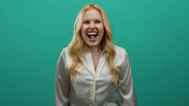 Sarışın genç bir kadın neşeli bir şekilde yeşil bir arka plana gülüyor. Bulaşıcı bir gülümsemesi var. Rahat bir atmosferde..