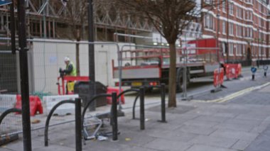 Şehir arka planı ve bokeh etkisi olan, sokak elemanlarını ön plana çıkaran ve iş kuran bulanık bir adam inşaat alanında.