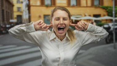 Kentsel bir sokakta, hayal kırıklığı içinde kulaklarını tıkayan bir kadın, şehir ortamında gürültüden rahatsız olduğunu ifade eden, beyaz gömlek giyen, güneşli bir arka plan.