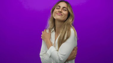 Genç sarışın kadın mor fotoğraf stüdyosunda omuzlarını nazikçe tutuyor..