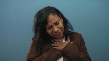 Afro-Amerikalı bir kadın bir elini göğsüne dayamış, kaşlarını çatmış ve dudaklarını mavi stüdyo duvarlarına dayamış, pek iyi görünmüyordu..