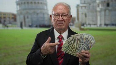 Bize dolar tutan kıdemli adam dışarıda servetini sergileyen sidik kulesinin önünde duruyor..