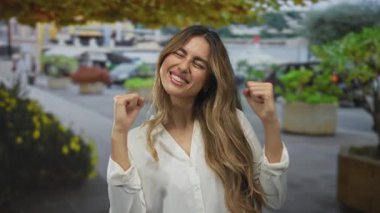 Şehir sokaklarında çıplak koluyla genç sarışın kadın yumruk pompası; sevinç zaferi kutlamaları heyecanı.