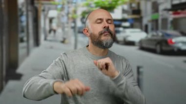Sakallı kel adam hareketli bir şehir caddesinde enerjik bir şekilde dans ediyor, canlı açık hava atmosferini ve dinamik hareketleri yakalıyor..