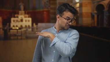 Kilisede burnu kapalı genç adam kötü koku işaret gözlük ve mavi gömlek, arka plan gösteriyor ki mimari unsurlar kutsal ayarı gösteriyor