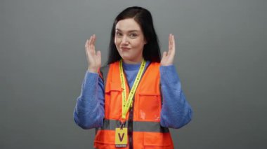 Gri arka planda elleri olan turuncu yelekli kadın toplum hizmeti ortamlarında gönüllülük ve iletişim tasvir ediyor.