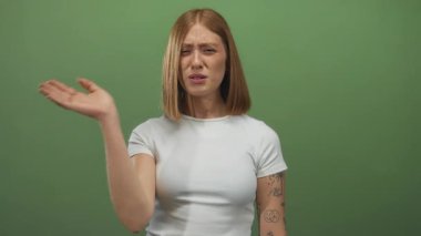 Sarışın genç bir kadın elini yeşil bir duvara sürerek burnunu kapatırken yüzünü buruşturur; iğrenme reddi.