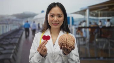 Gezideki genç Çinli kadın doktor dışarıda kalp ve beyin modelleri tutuyor..