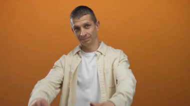 Turuncu duvara karşı yapılan çerçeveli jest, gelişigüzel bir ortamda yaratıcı görüşü izole ediyor..