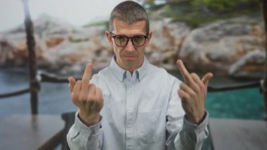 Restoran terasındaki adam rıhtımda ciddi bir ifadeyle el hareketi yapıyor..