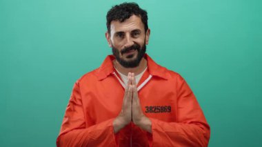 Turuncu hapishane tulumlu İspanyol sakallı adam yeşil bir geçmişe karşı dua ediyor. Hapis içinde umut ve iç gözlem taşıyor..