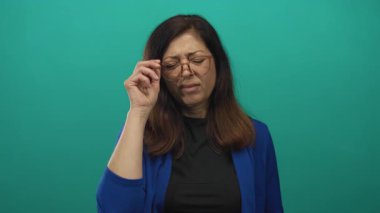 Orta yaşlı bir kadın gözlüğünü çıkarır ve tutar. Sonra da stüdyoda şaşı gözlerle burnunu sıkar. İğrenme..