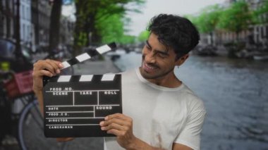 Beyaz gömlek giyen ve şehrin caddesinde bir kanalın yanında gülümseyen bir adam..