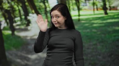 Ağaçların arasından süzülen güneş ışığıyla yemyeşil bir parkta sallanan bir kadın açık hava manzarası sergiliyor..