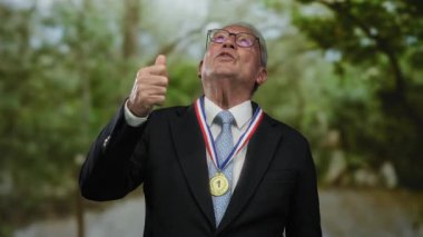 Takım elbiseli kıdemli bir adam, bir park ortamında, açık hava iş bağlamında başarı ve kendine güvenini gösteriyor..