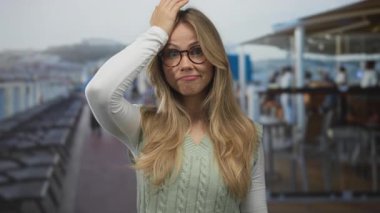 Kafkasyalı sarışın, uzun saçlı, gözlüklü, geniş güvertede kafaya dokunan bir kadın..