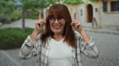 Güneşli bir günde şehir sokaklarında gülümseyen İspanyol kıdemli bir kadın, şehir dışındaki bir ortamda neşe ve pozitifliği vurguluyor..