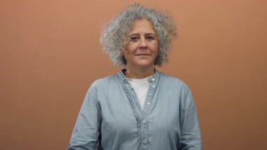 Kahverengi duvara karşı hareket eden bir kadın basit bir çevrede düşünceli ve bilge olduğunu gösterir. Günlük kıyafetler giyer ve kendine güvenini ve duygularını gösterir..