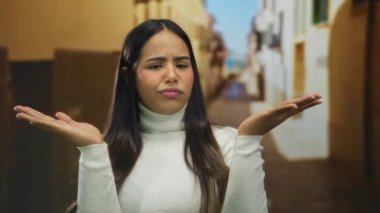 Kadın elleri omuz silkme kenti Latin kökenli açık hava şaşkın genç yüz ifadesi dar kaldırım taşlarında yakalandı..