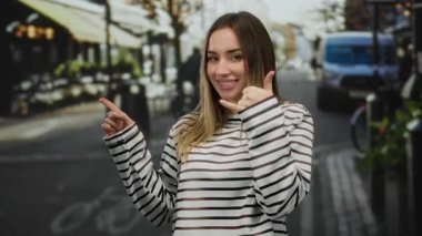 Sokakta gülümseyen bir kadın şehir ortamında çizgili tişört giyip şehir ortamında hareketlilik gösteren enerjik bir hava yaratıyor..