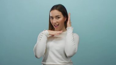 Mavi arka planda neşeli pozlar veren bir kadın canlı ifadeler ve hareketlerle genç enerjisini ve dinamik varlığını gösteren beyaz bir kıyafet içinde..