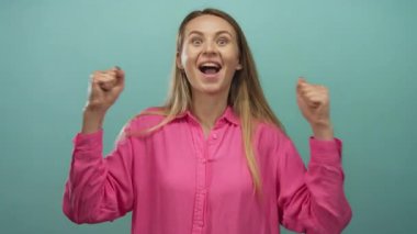 Mutluluk ve başarıyı ifade eden kollarıyla yeşil arka planda pembe gömlekli bir kadın sevinçle kutluyor..