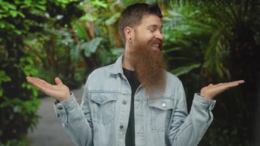 Kot ceket giyen adam orman yolunda yoğun yeşillikler arasında ellerini açık tutuyor; dinginlik dengesi.