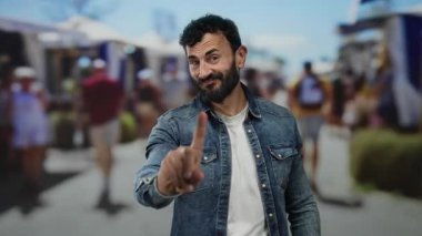 Sokak ortasında sakallı İspanyol bir adam. Çevresi insanlarla çevrili, hareketli şehir ortamında parmağıyla hareket etmiyor..