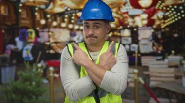 Yansıtıcı yelek giymiş genç bir adam ve parlak bir şehir caddesinde parmaklarıyla parmakla işaret ederek, kentsel açık hava ayarlarının çekici bir ifadeyle canlı bir tasvirini sunuyor..