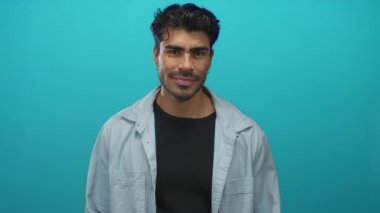 Genç İspanyol adam bir turkuaz duvarın önünde avuç içini açık tutuyor ve güvenle gülümsüyor; açıklık.