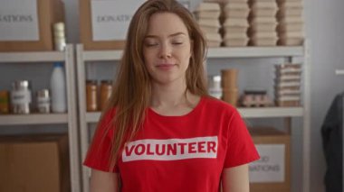 Kırmızı gönüllü gömleği giyen bir kadın, bağış merkezi binasında karton kutularla gülümsüyor; cömertlik..