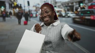 Alışveriş torbasıyla gülümseyen bir kadın şehrin hareketli caddesinde şehir yaşam tarzını ve açık havada neşeli alışveriş deneyimini gösteriyor..