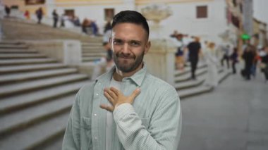 Kentsel sokak ortamında genç bir İspanyol arka planda bulanık şehir basamaklarıyla yüz ifadeleri yapıyor, şehir yaşamını ve dışardaki ifadeleri sergiliyor..