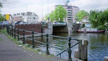 Amsterdam 'daki bulanık kanal görüntüsü. Çözünmüş binalar ve yeşil ağaçlar Bokeh arka planında sakin bir Hollanda manzarası oluşturuyor..