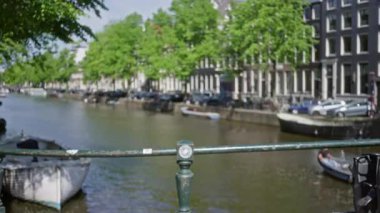 Yeşil ağaçlı, tekneli ve suyu kaplayan binalı Amsterdam Kanalı 'nın bulanık görüntüsü Hollanda' daki Bokeh etkisi ve sakin şehir manzarasını gözler önüne seriyor..