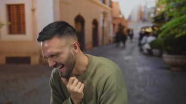 Genç İspanyol adam neşeli bir şekilde gülüyor şehir caddesinde.