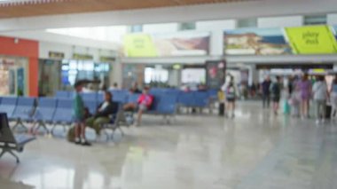 Havaalanı terminalinde sırt çantalı bulanık bir kadın ve arka planda bekleyen gezginler.