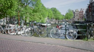 Yeşil ağaçlar ve geleneksel mimari ile bulanık bir kanal boyunca dizilmiş bisikletler, Hollanda kentsel manzarasının kalbinde rüya gibi, çözülmüş bir zemin oluşturuyor..