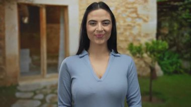 Genç bir kadın açık hava taş avlusunda neşeli bir ifadeyle neşeli bir şekilde hareket ediyor, neşeli bir atmosfer ve enerjik bir enerjiyi vurguluyor..