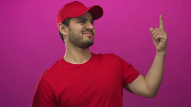 Kırmızı tişörtlü ve şapkalı genç İspanyol teslimatçı parmağını morumsu stüdyoda sallıyor..